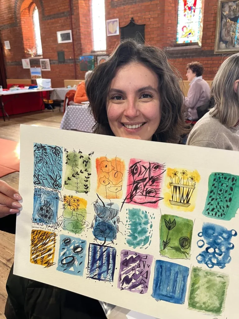 Art class student smiling and displaying colourful mixed media artwork